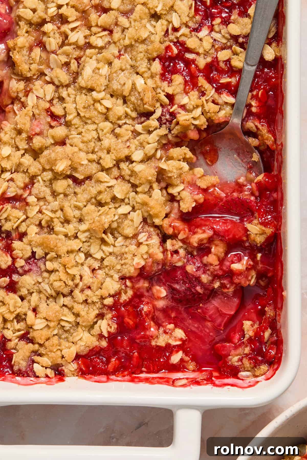 Crimson Crumble Dream 3 Spoon scooping into strawberry crisp in baking dish.