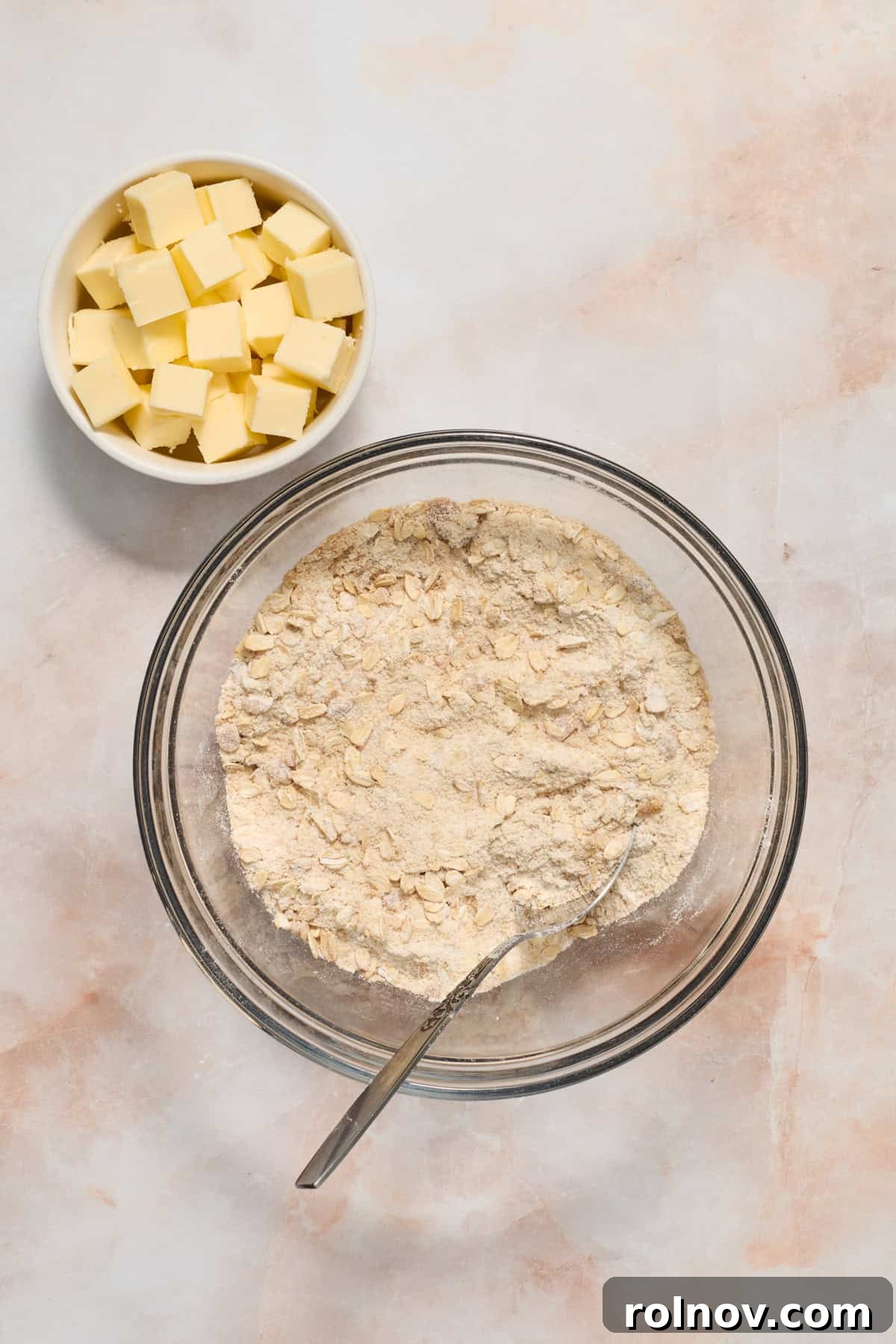 Crimson Crumble Dream 5 Flour, oats and brown sugar mixed in glass bowl with cubed butter in bowl to the side.