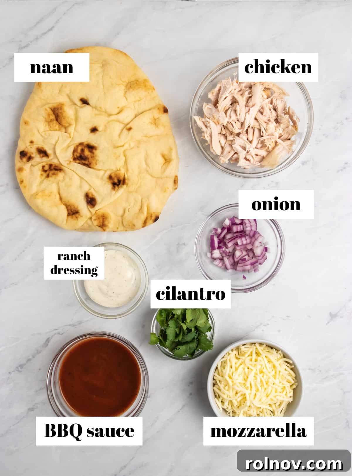 Smoky BBQ Ranch Chicken Flatbread 3 Individual ingredients for BBQ Ranch Chicken Flatbread, including naan, cooked chicken, ranch dressing, BBQ sauce, mozzarella, red onion, and fresh cilantro, neatly arranged on a kitchen counter.
