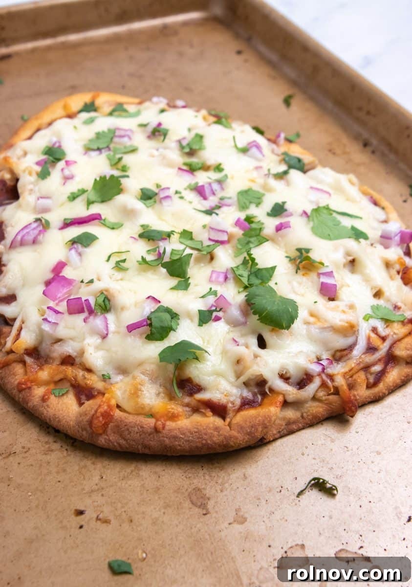 Smoky BBQ Ranch Chicken Flatbread 5 Freshly baked BBQ chicken flatbread on a baking pan, generously topped with vibrant fresh cilantro, showcasing its crispy edges and melted cheese.