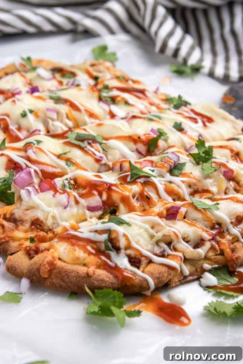 Smoky BBQ Ranch Chicken Flatbread 6 BBQ chicken flatbread on wax paper, expertly sliced into wedges and drizzled with a rich combination of ranch and BBQ sauce, highlighting its readiness to be served.