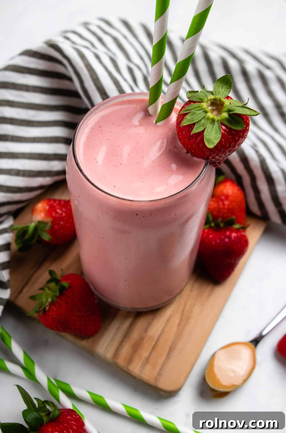 Strawberry Nut Bliss Smoothie 5 Strawberry Peanut butter smoothie in glass with green straws and strawberry garnish.