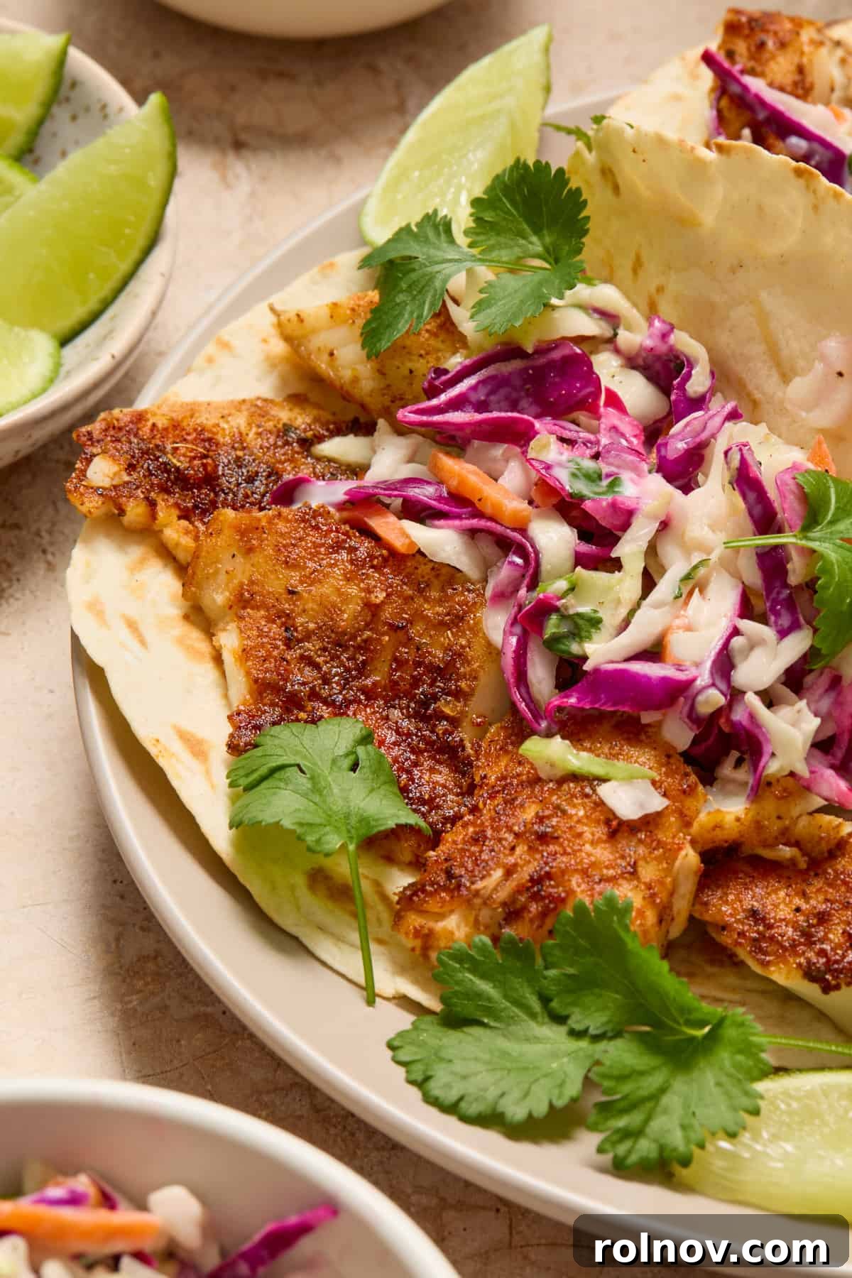 Crispy Air Fried Fish Tacos and Zesty Cilantro Lime Slaw 2 Air fryer fish tacos on white plate with slaw and fresh cilantro.