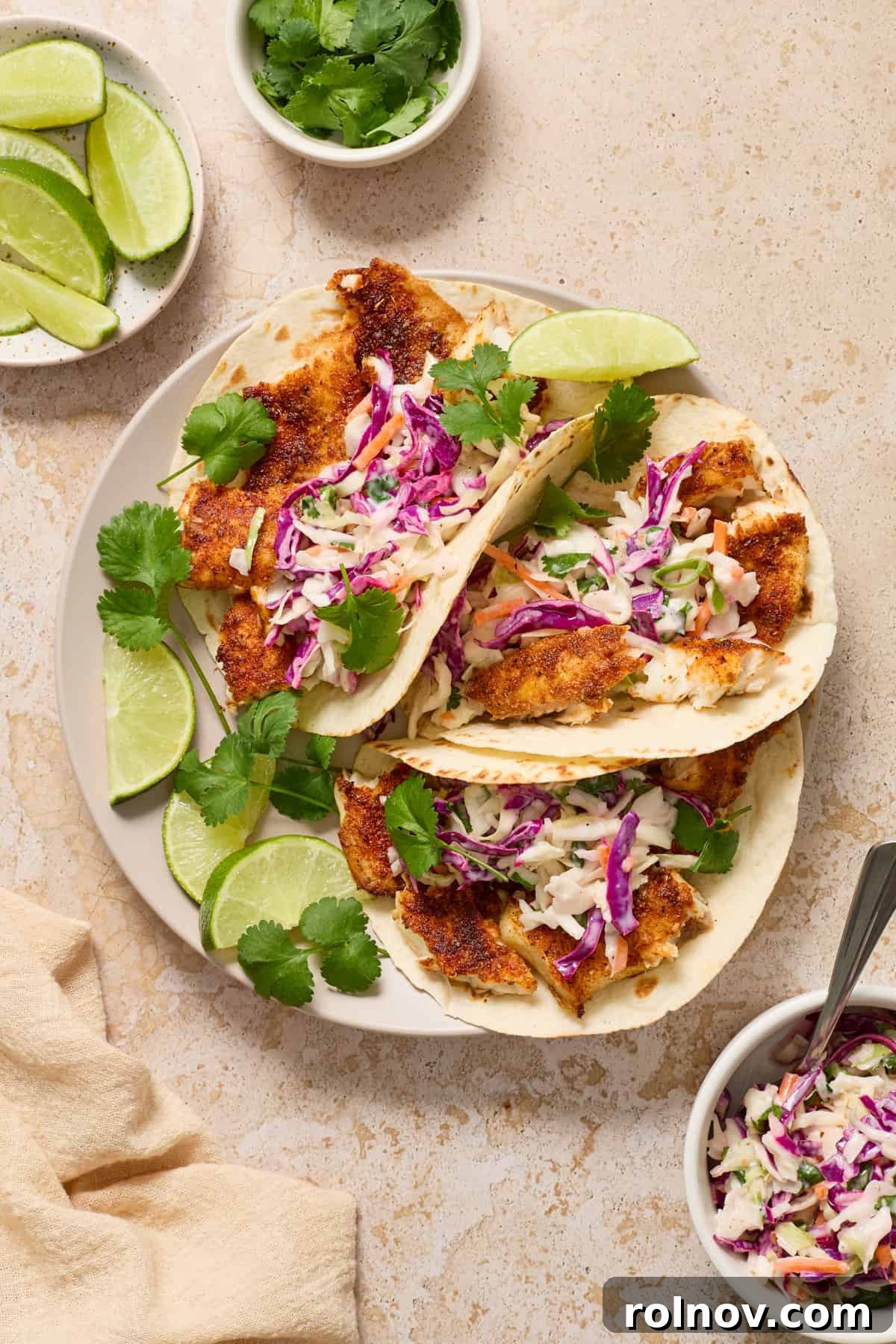 Crispy Air Fried Fish Tacos and Zesty Cilantro Lime Slaw 3 Air fryer fish tacos on white plate with lime.