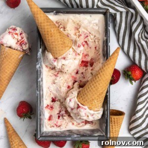 Easy Homemade No-Churn Strawberry Delight 7 Overhead view of strawberry ice cream in a container with sugar cones and fresh strawberries for garnish.