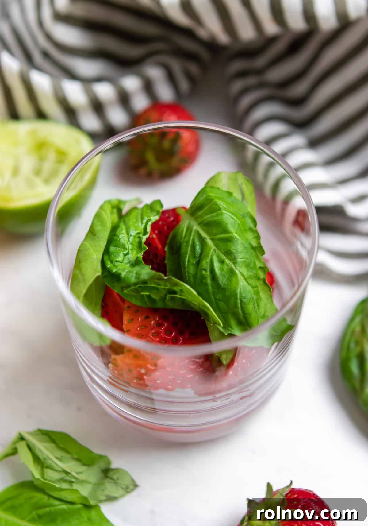 Garden Fresh Strawberry Basil Margarita 4 Strawberries and basil in glass before muddling.