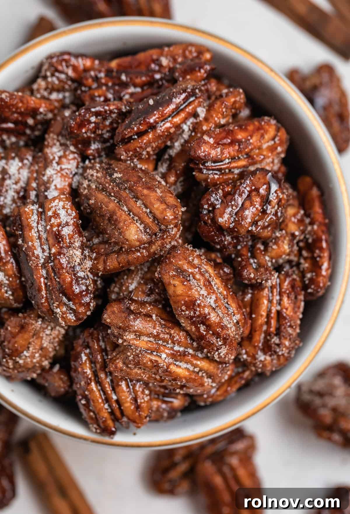 Overhead view of a beautiful ceramic bowl filled with golden-brown maple candied pecans, showcasing their delicious texture and readiness to be savored.