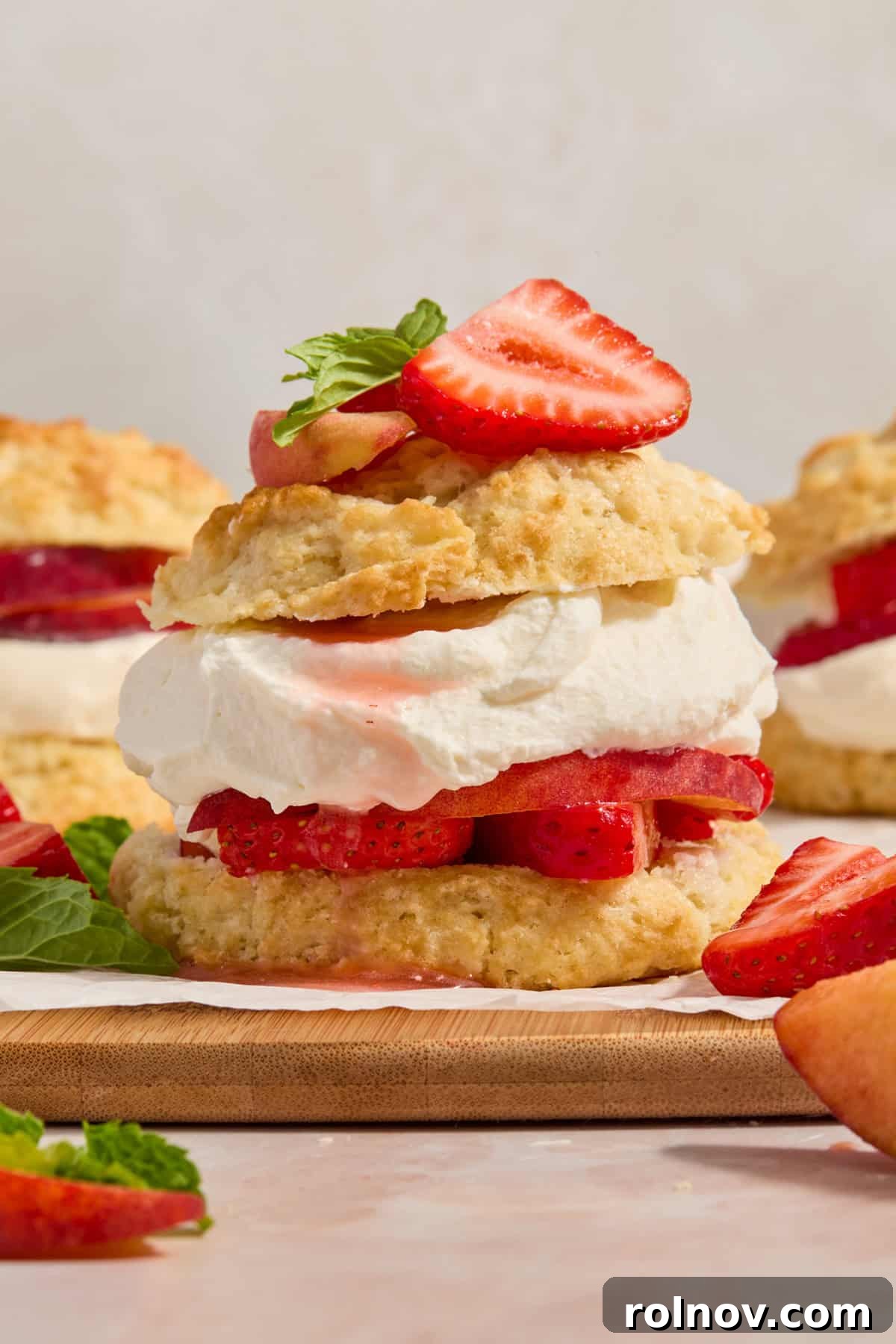 Sun-Kissed Peach Strawberry Shortcake 2 Strawberry peach shortcake on white parchment on board with fresh mint leaves.