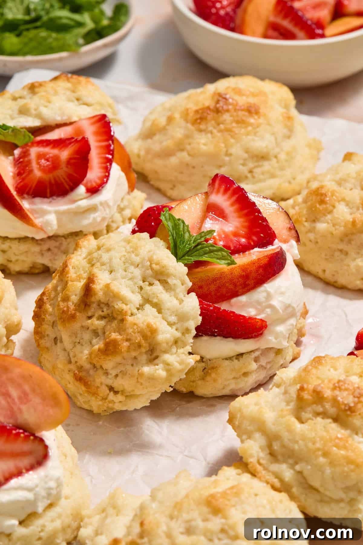 Sun-Kissed Peach Strawberry Shortcake 14 Peach and strawberry shortcakes layered with whipped cream and biscuit tops propped to the side of bottom half.