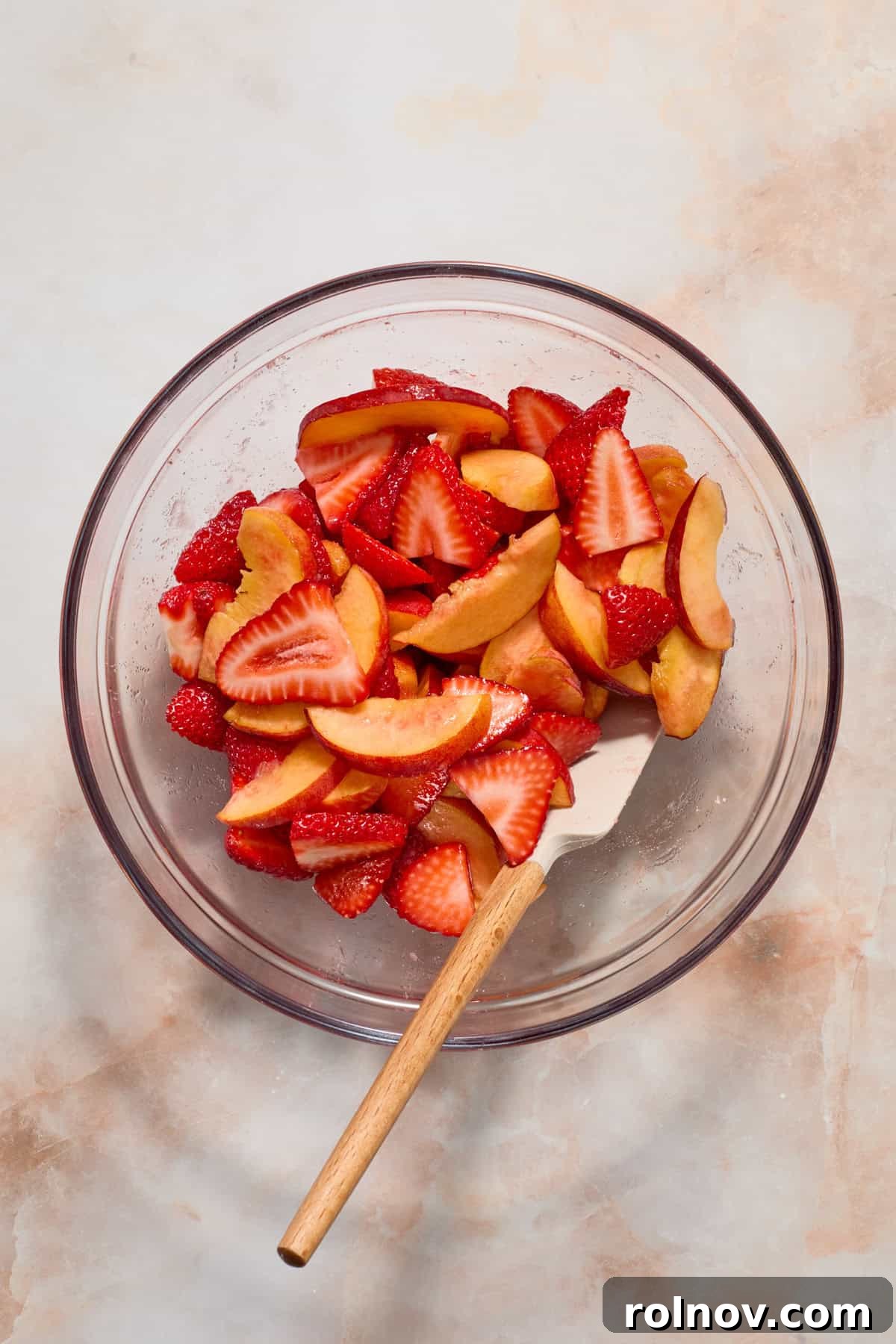 Sun-Kissed Peach Strawberry Shortcake 4 Strawberries and peaches in glass bowl with spatula.