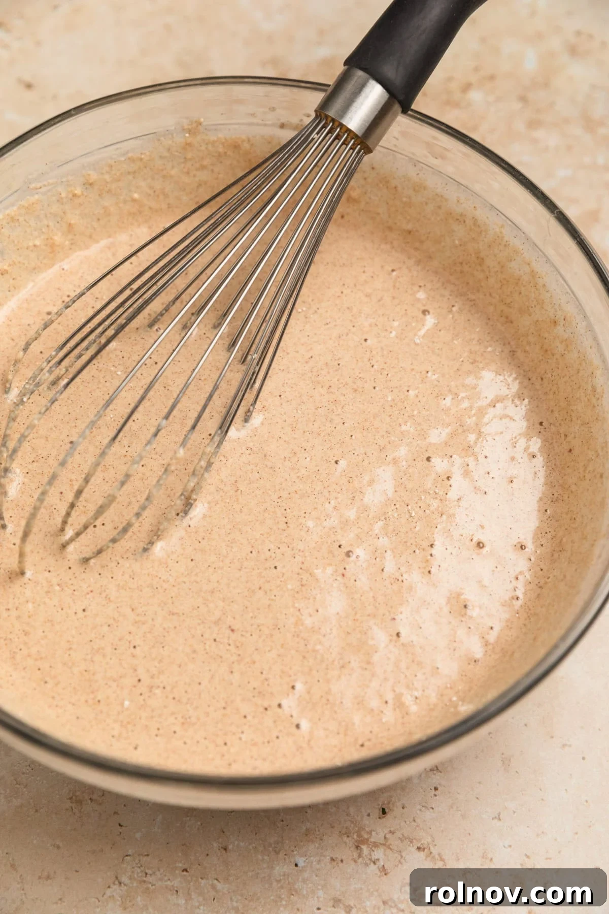 Spiced Apple Oat Pancakes 10 A bowl of apple oatmeal pancake batter with a whisk in it, showing ideal consistency.