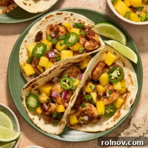 Tropical Shrimp Tacos with Mango Salsa 14 Three shrimp tacos on green plate topped with a salsa made of diced mango, onion and jalapeños.