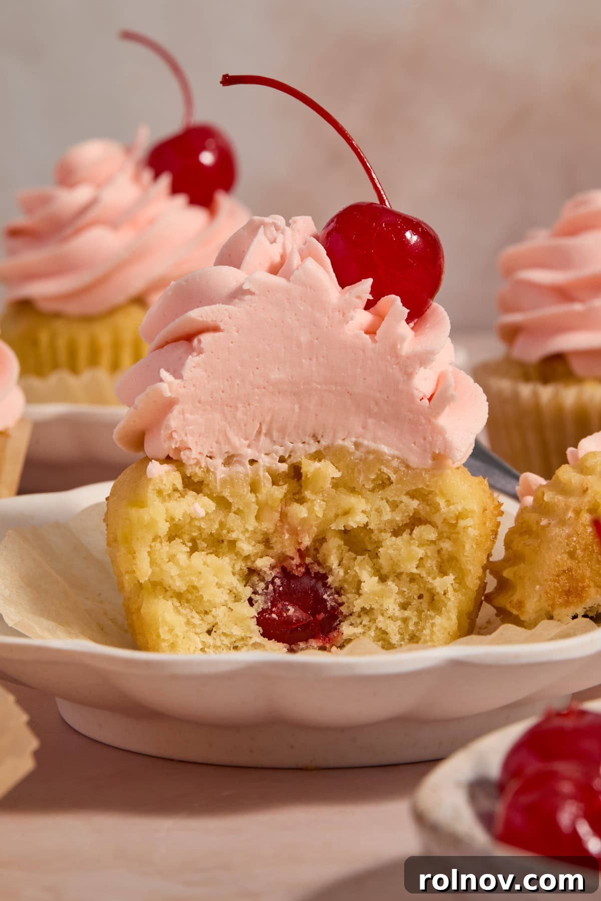 Golden Pineapple Cherry Bliss 8 Pineapple cupcake with cherry inside topped with cherry frosting on plate.