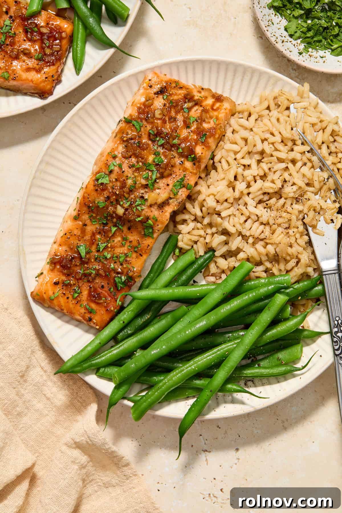 Citrus glazed salmon filet on plate with green beans and brown rice.