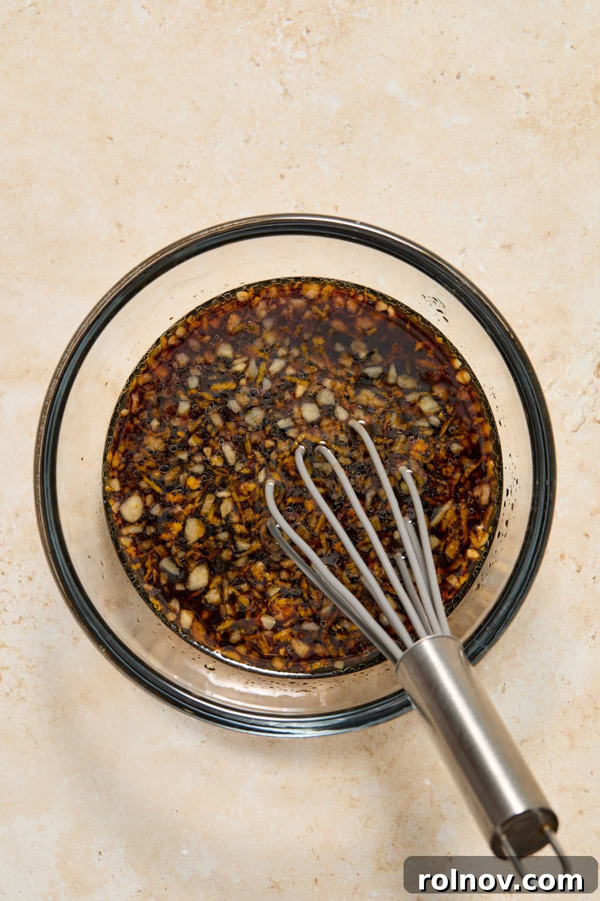 Maple citrus glaze in glass bowl with whisk.
