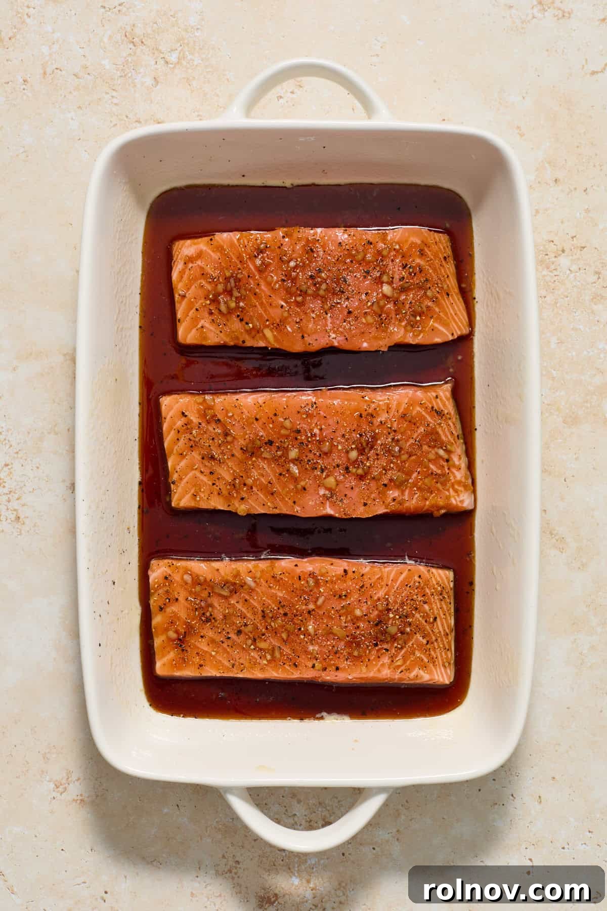 Salmon topped with maple glaze in baking pan.