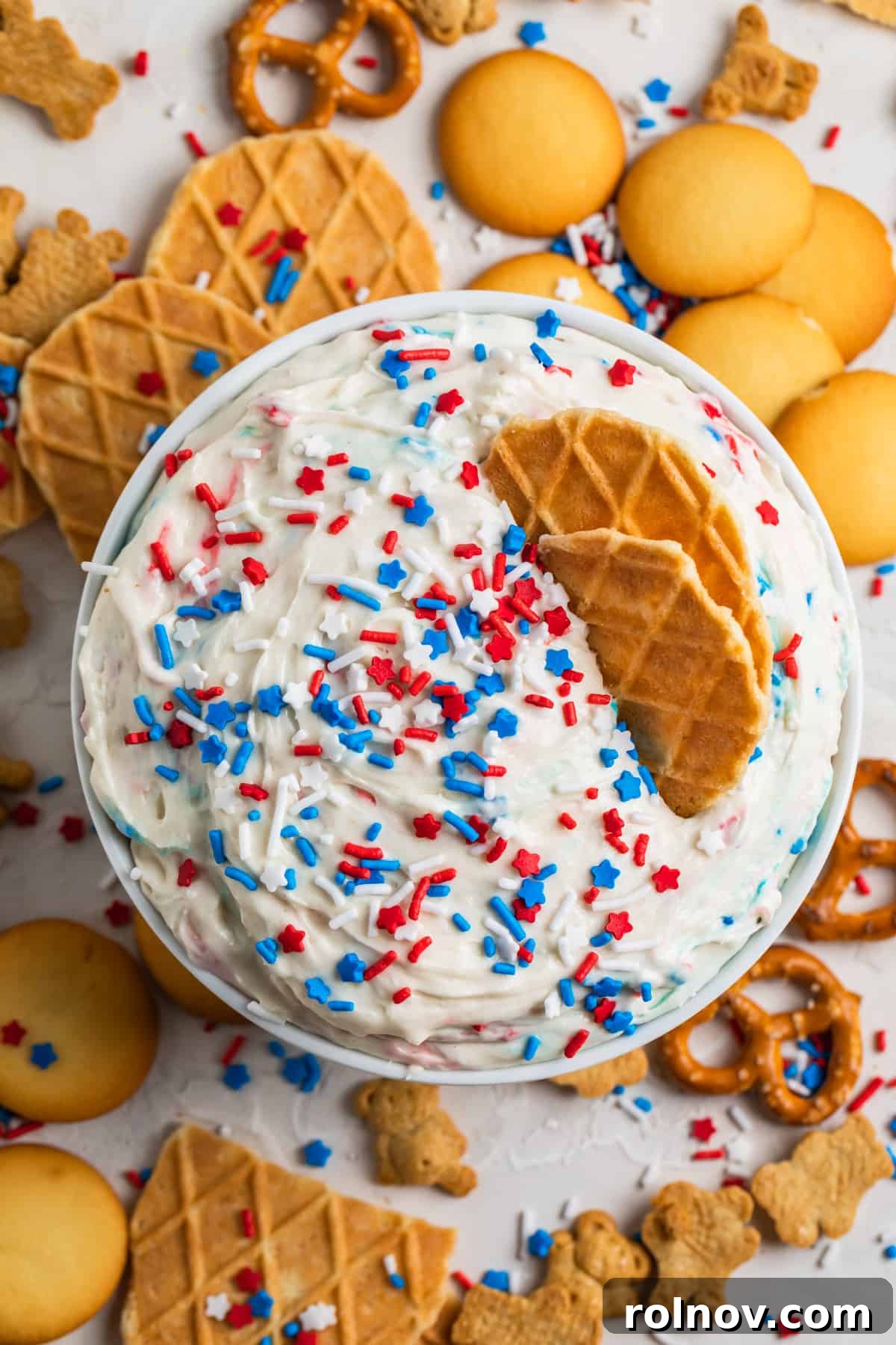 Celebration Funfetti Dip 3 Dunkaroo dip in white bowl with red, white and blue sprinkles on top and cookies and pretzels surrounding.
