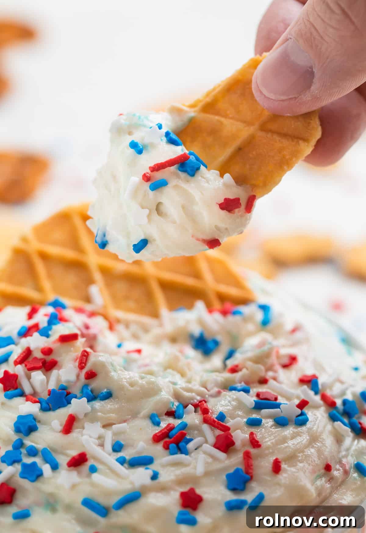 Celebration Funfetti Dip 8 Waffle cookie piece with patriotic funfetti dip on end topped with red, white and blue sprinkles.