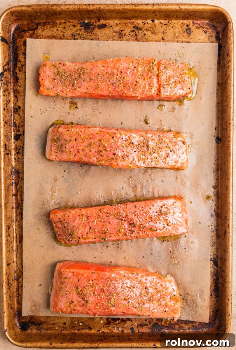 Zesty Greek Salmon & Herb Rice Bowls 4 Salmon filets on parchment lined baking pan topped with olive oil and seasoning before baking.