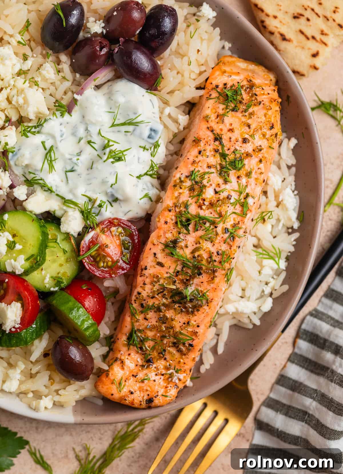 Zesty Greek Salmon & Herb Rice Bowls 8 Overhead view of Greek salmon rice bowls with feta, kalamata olives, tomatoes, cucumbers and more.