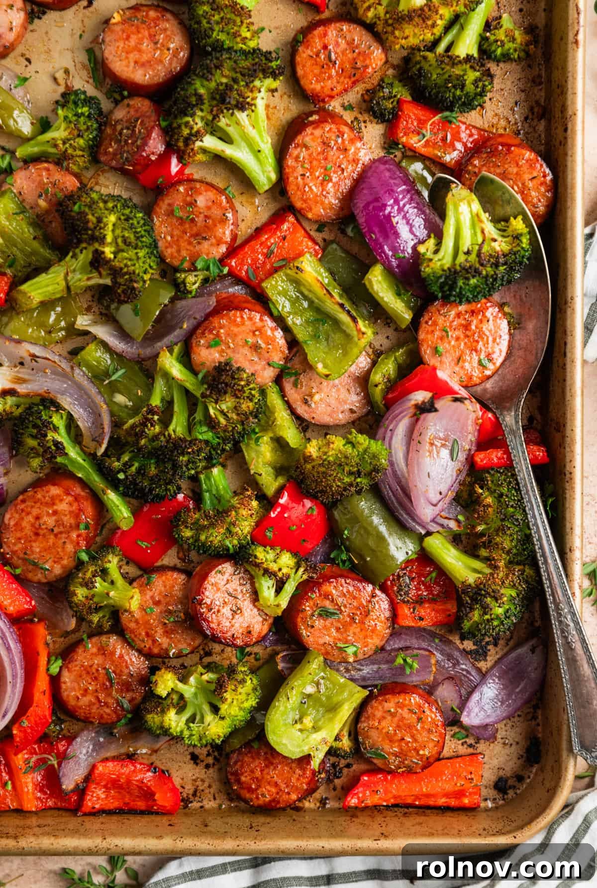 Roasted Sausage & Veggie Sheet Pan Supper 2 Sausage sheet pan dinner with serving spoon scooping into the food.
