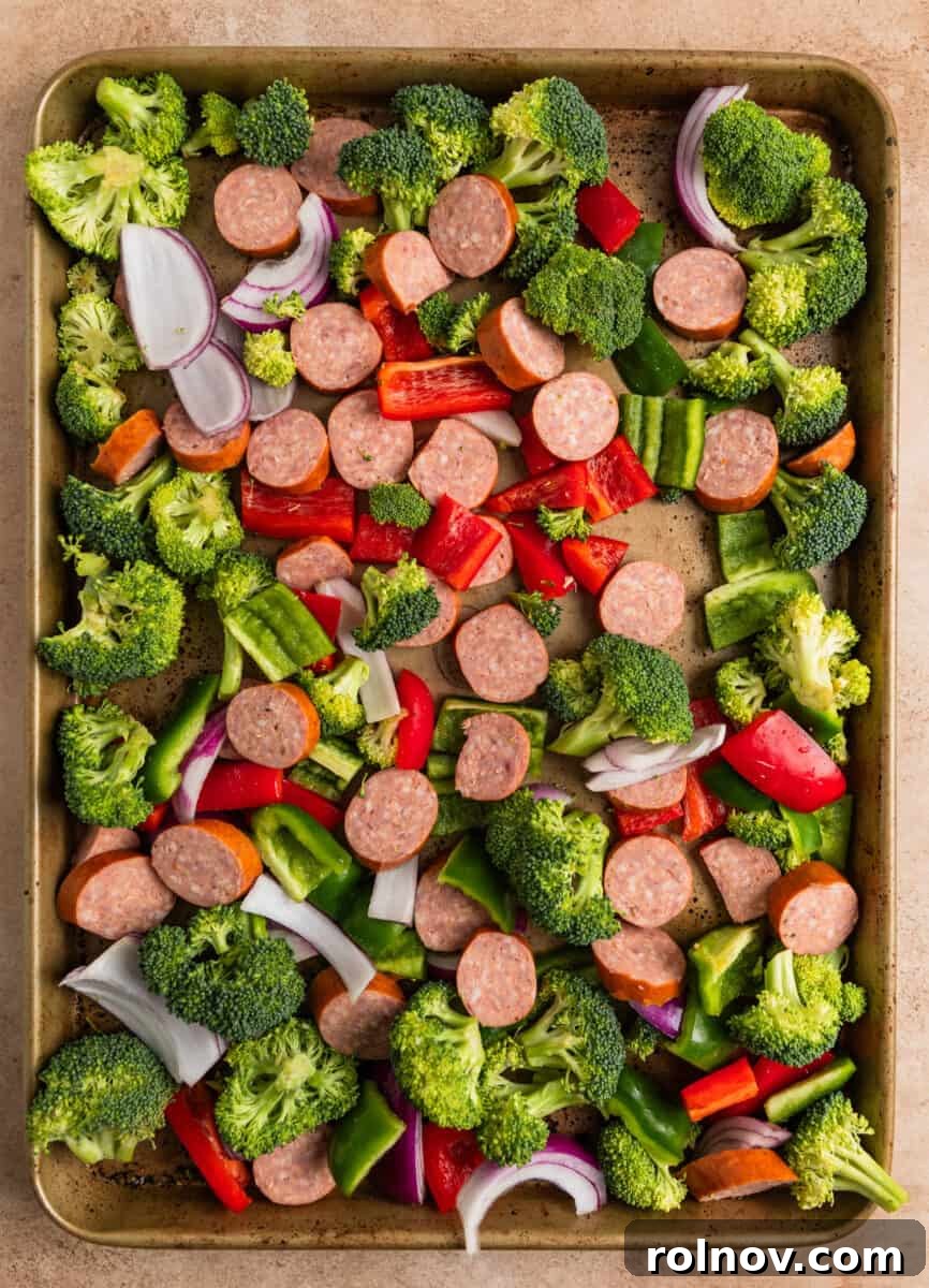 Roasted Sausage & Veggie Sheet Pan Supper 4 Kielbasa sausage sliced, chopped peppers and broccoli and onions on sheet pan.