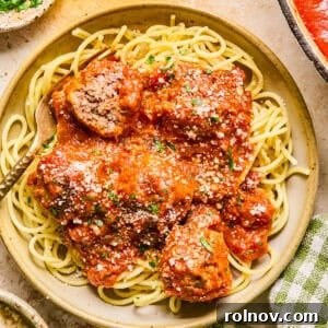 Plate with spaghetti and meatballs topped with fresh parmesan.