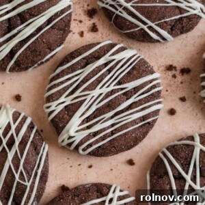 Chocolate cake mix cookies with white chocolate drizzle surrounded by cookie crumbs.