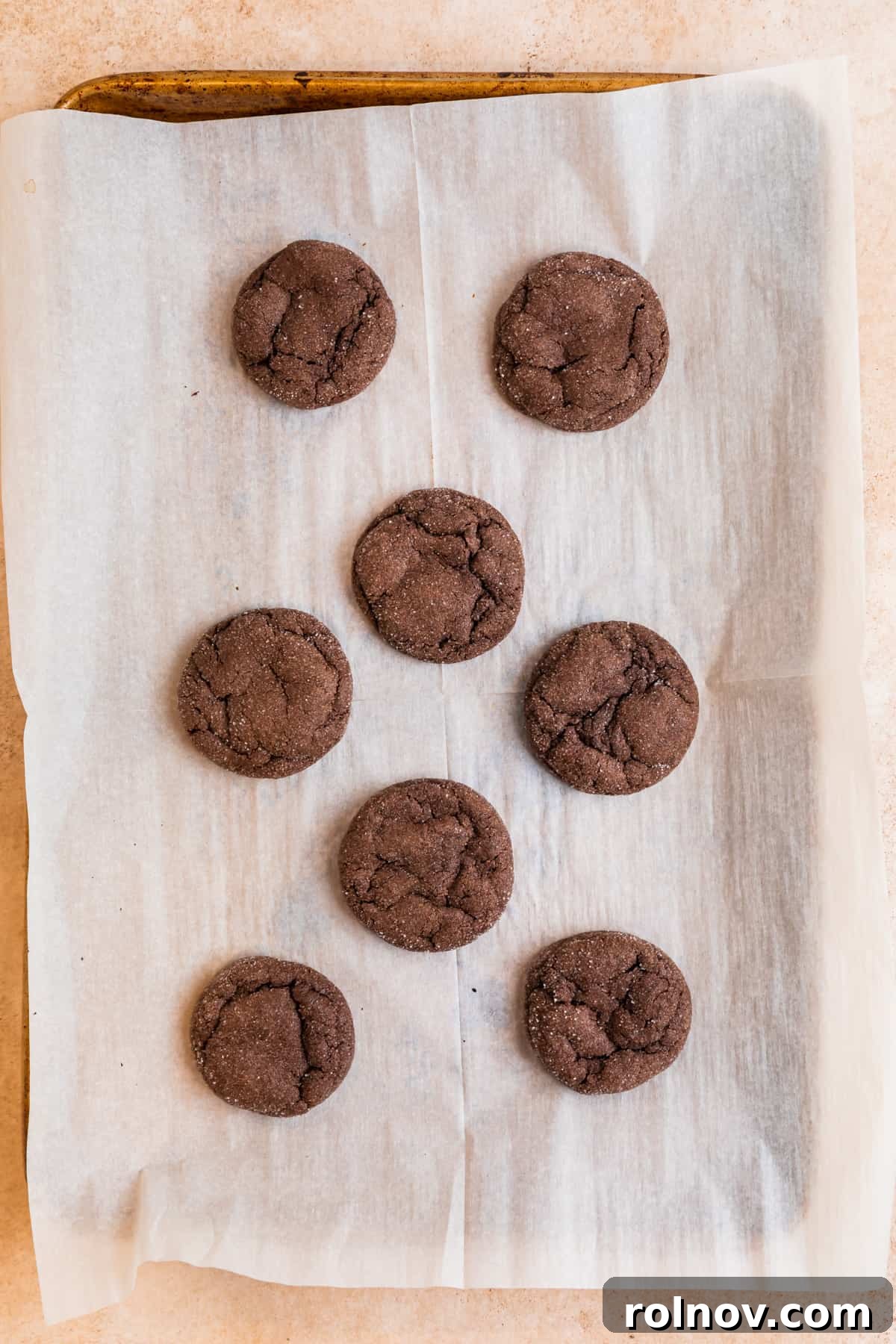 Effortless Chocolate Cake Mix Treats 7 Freshly baked chocolate cake mix cookies, perfectly crinkled, cooling on a parchment-lined cookie sheet, ready for final touches.