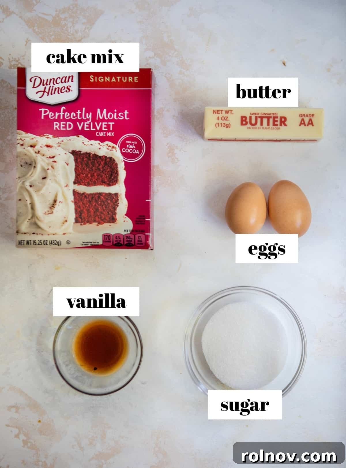Scarlet Velvet Cake Mix Cookies with Tangy Cream Cheese Frosting 3 Organized ingredients for red velvet cake mix cookies, including butter, eggs, vanilla, and cake mix on a clean kitchen counter.