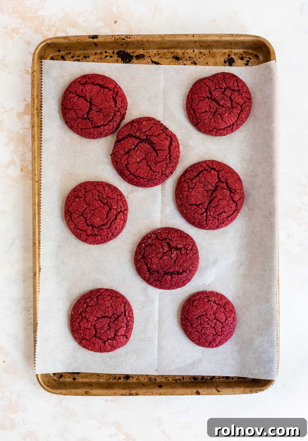 Scarlet Velvet Cake Mix Cookies with Tangy Cream Cheese Frosting 5 Freshly baked red velvet cake mix cookies with crinkled tops cooling on a baking sheet.