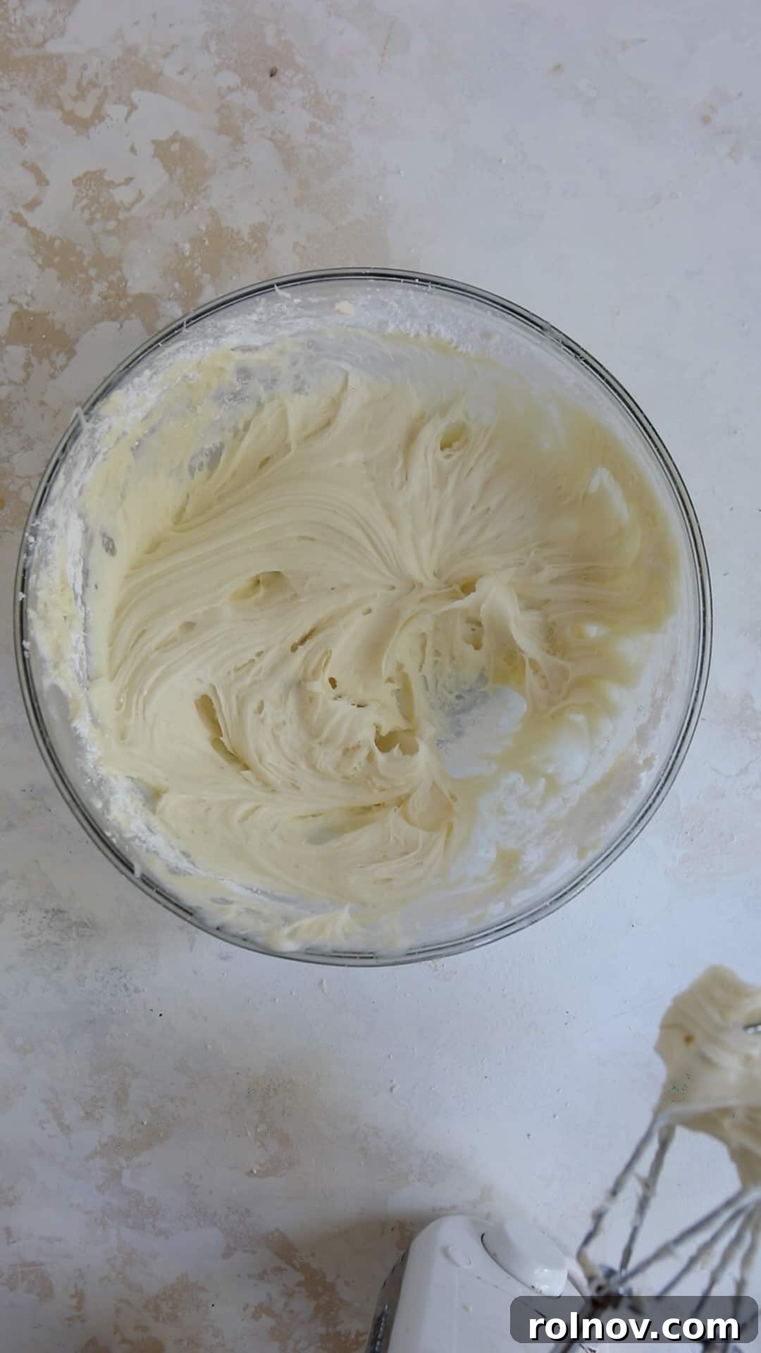 Scarlet Velvet Cake Mix Cookies with Tangy Cream Cheese Frosting 6 Cream cheese icing being prepared in a mixing bowl with an electric mixer beside it, ready for frosting.