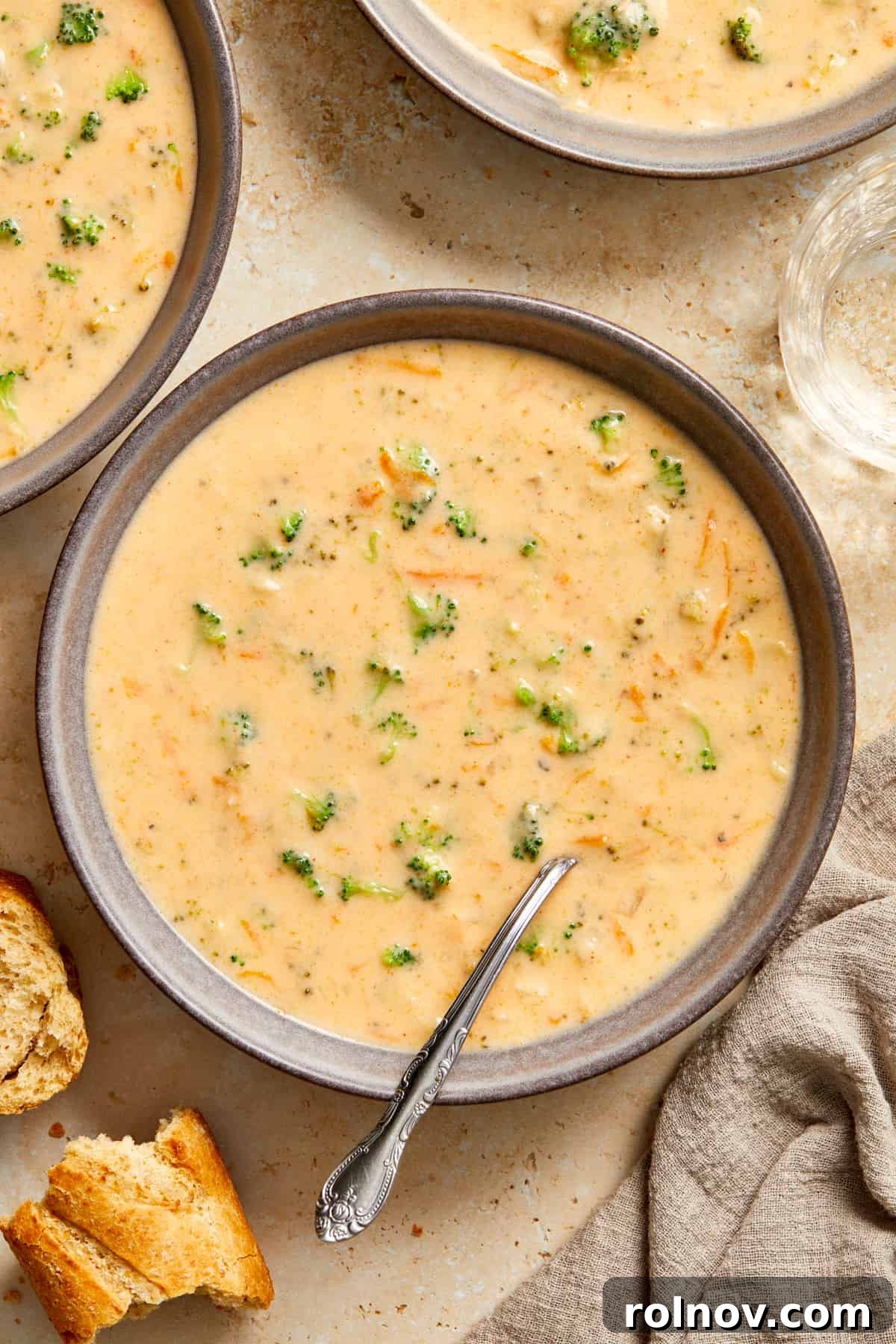 Creamy Instant Pot Broccoli Cheddar Soup 2 A gray ceramic bowl filled with creamy Instant Pot Broccoli Cheddar Soup, garnished with a sprinkle of fresh parsley and served with a crusty piece of bread on the side.