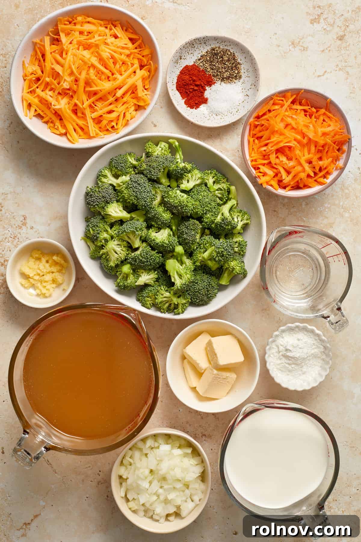 Creamy Instant Pot Broccoli Cheddar Soup 3 A vibrant flat lay of fresh carrots, a block of sharp cheddar cheese, creamy butter, rich broth, and crisp broccoli florets, perfectly arranged to showcase the core ingredients for this delicious soup recipe.