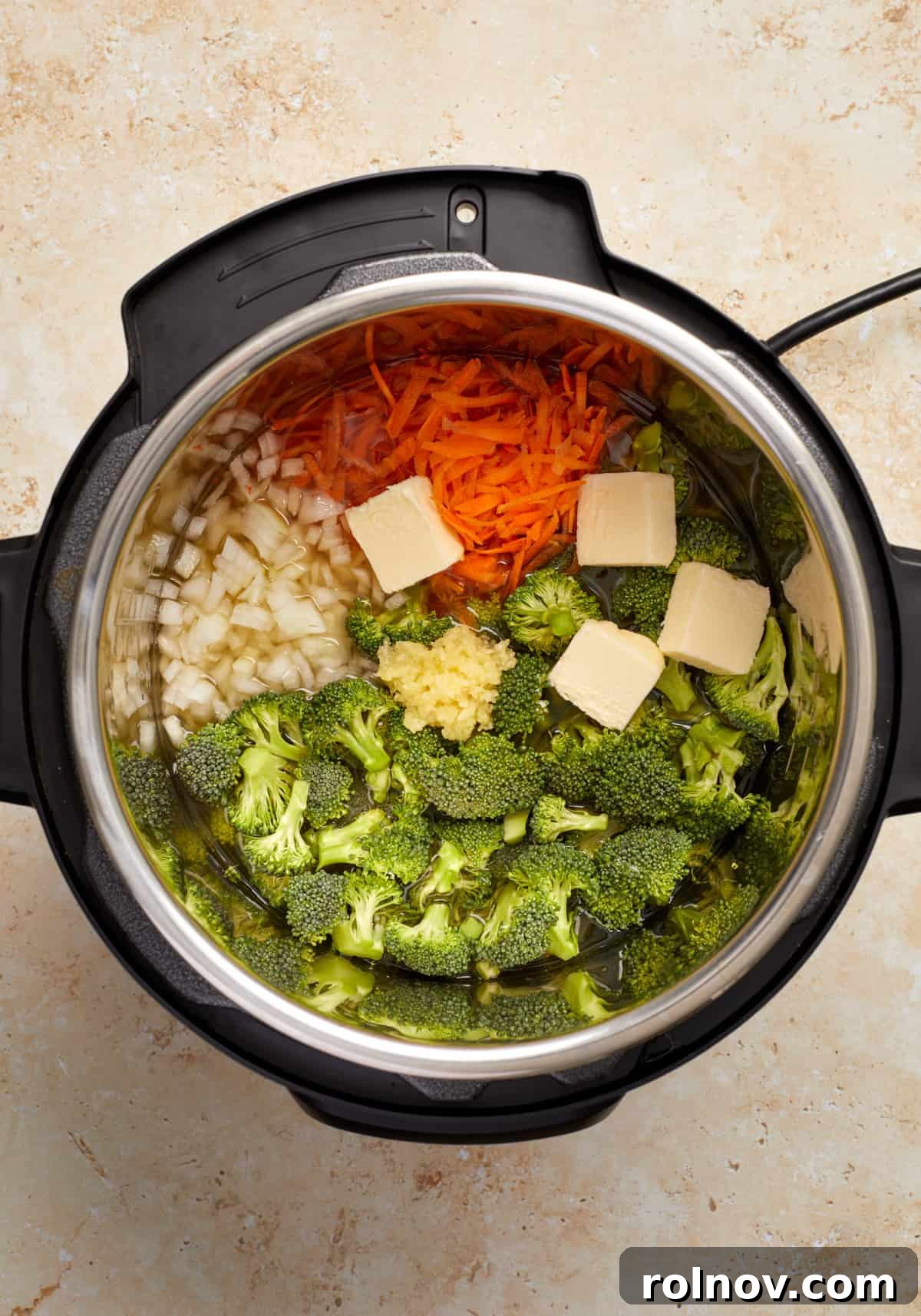 Creamy Instant Pot Broccoli Cheddar Soup 4 Freshly chopped broccoli, shredded carrots, diced onion, a dollop of butter, and minced garlic are ready in the Instant Pot liner, awaiting the next steps for a flavorful soup.
