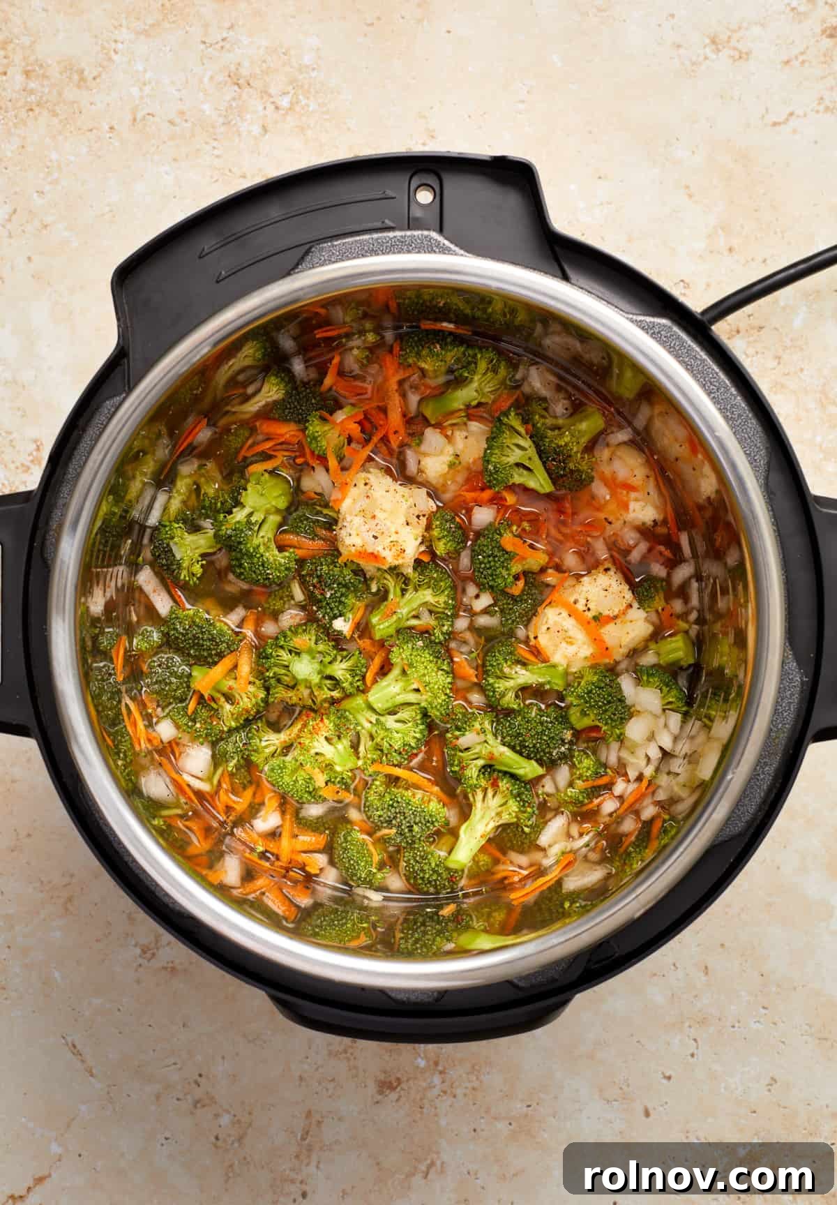 Creamy Instant Pot Broccoli Cheddar Soup 5 The Instant Pot contains broccoli, carrots, onion, broth, and other seasonings, perfectly prepped before sealing and pressure cooking to create a delicious soup.