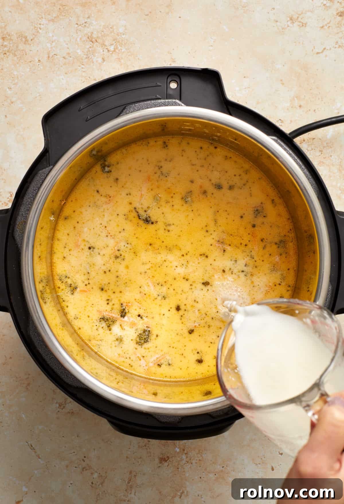 Creamy Instant Pot Broccoli Cheddar Soup 8 A cornstarch slurry, whisked smooth, is being carefully poured into the bubbling broccoli cheddar soup in the Instant Pot to thicken it to the desired consistency.