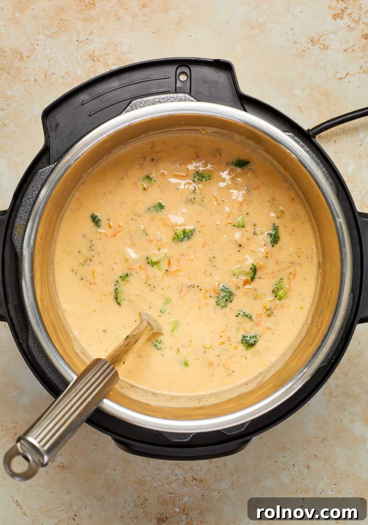 Creamy Instant Pot Broccoli Cheddar Soup 9 The Instant Pot filled with perfectly thickened broccoli cheddar soup, ready to be served, with a ladle resting inside.