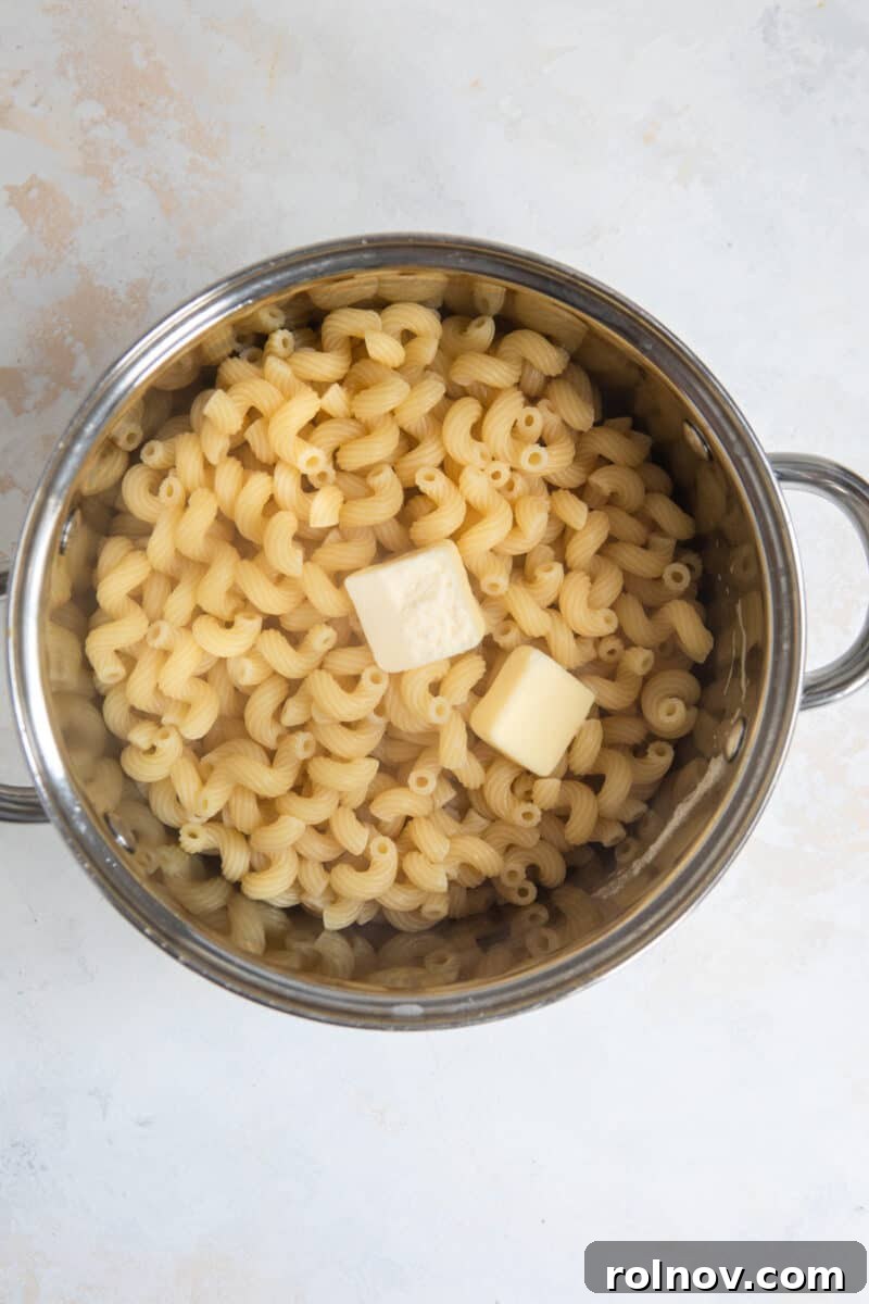 Gourmet Cheddar Gruyère Mac and Cheese 4 Pot with cooked pasta and butter.