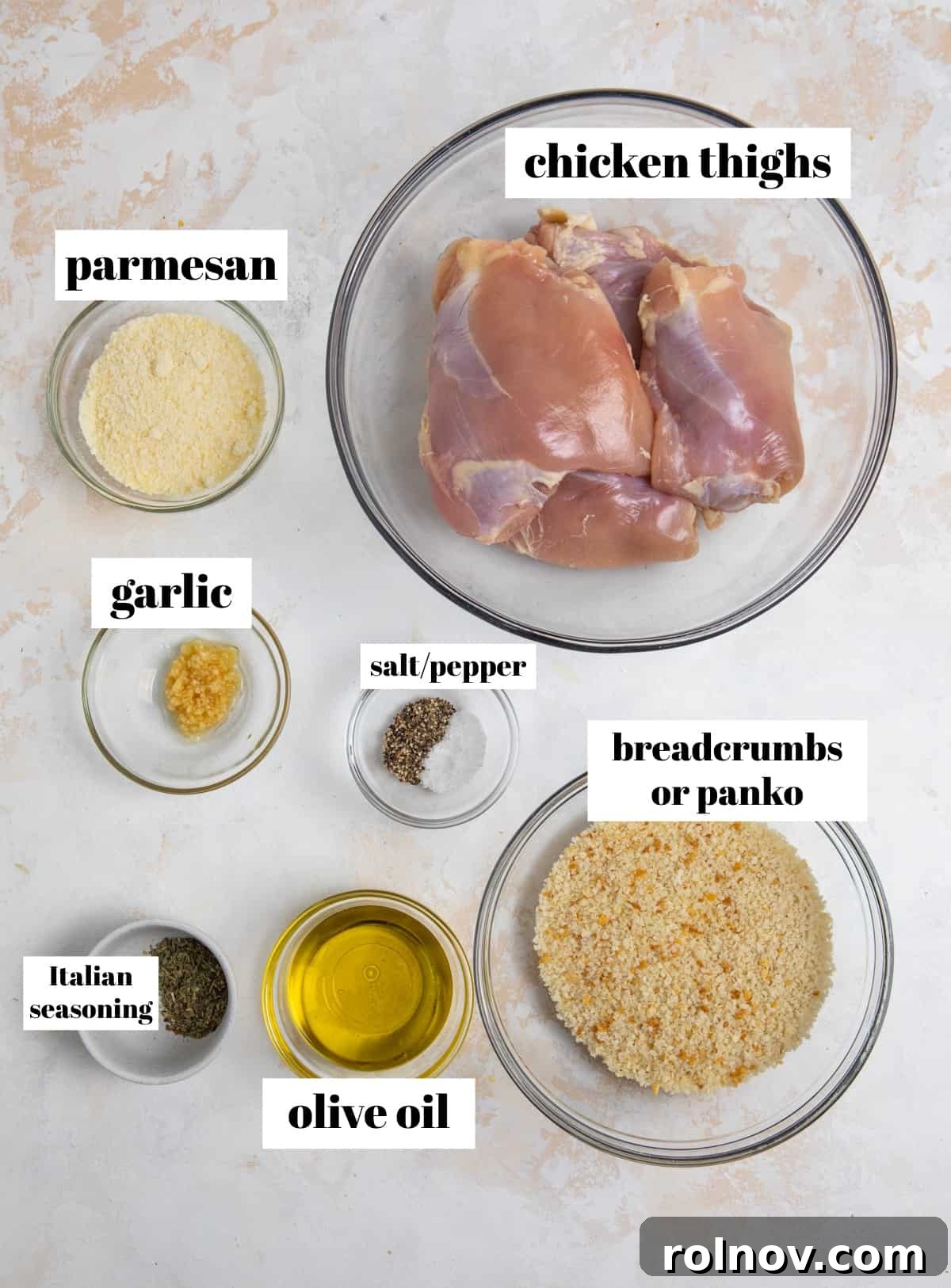 Crispy Parmesan Air Fryer Chicken Thighs 3 A collection of essential ingredients including grated Parmesan cheese, a bottle of olive oil, breadcrumbs, and various spices, laid out on a surface, ready to make air fryer chicken thighs.
