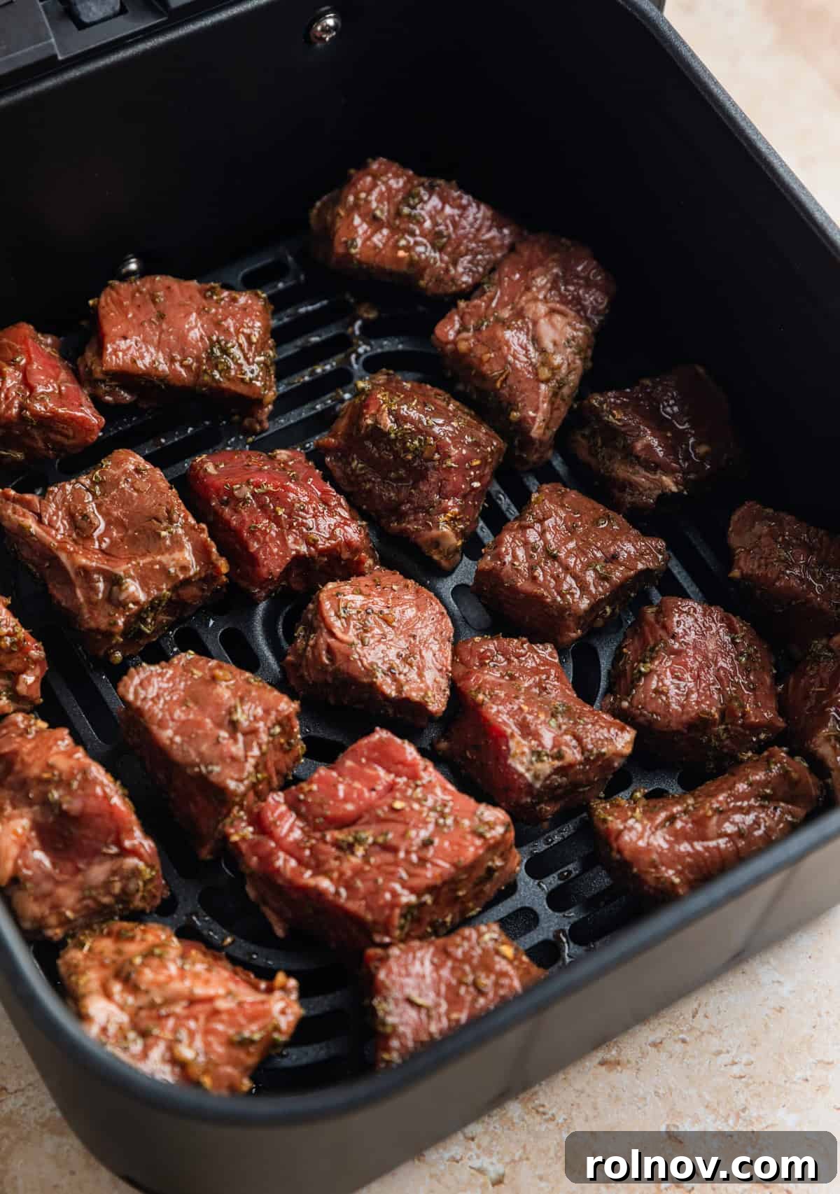 Succulent Air Fryer Steak Bites 7 Marinaded sirloin steak bites in air fryer basket before cooking.