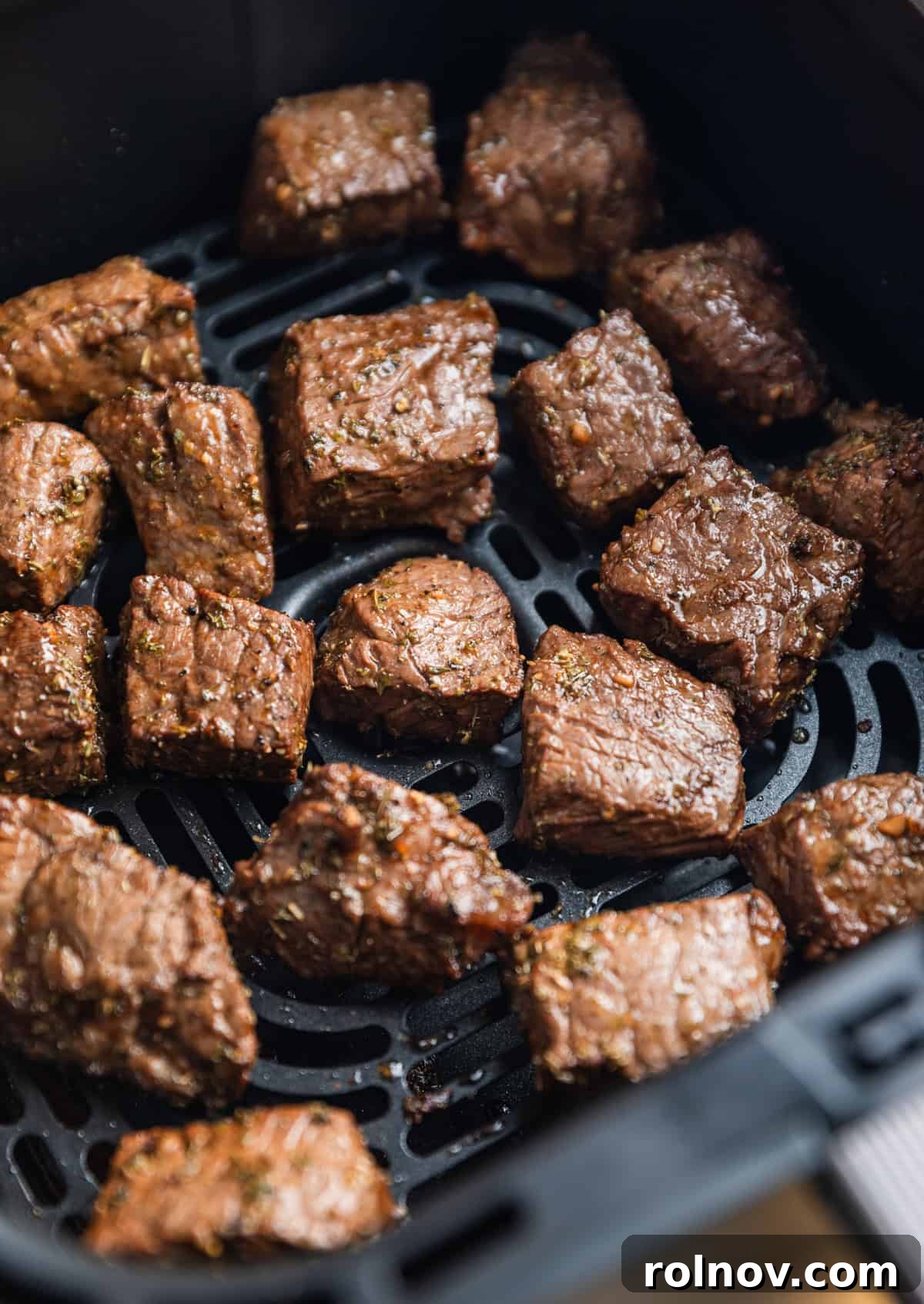 Succulent Air Fryer Steak Bites 8 Cooked chunks of sirloin in air fryer basket.