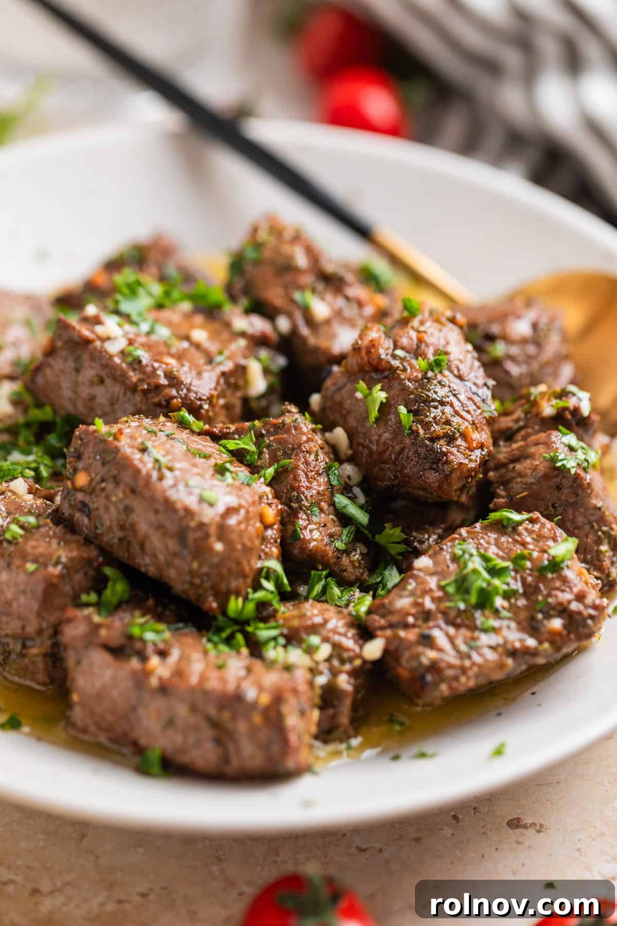 Succulent Air Fryer Steak Bites 10 White ceramic plate with air fryer steak bites tossed with lemon garlic butter sauce.
