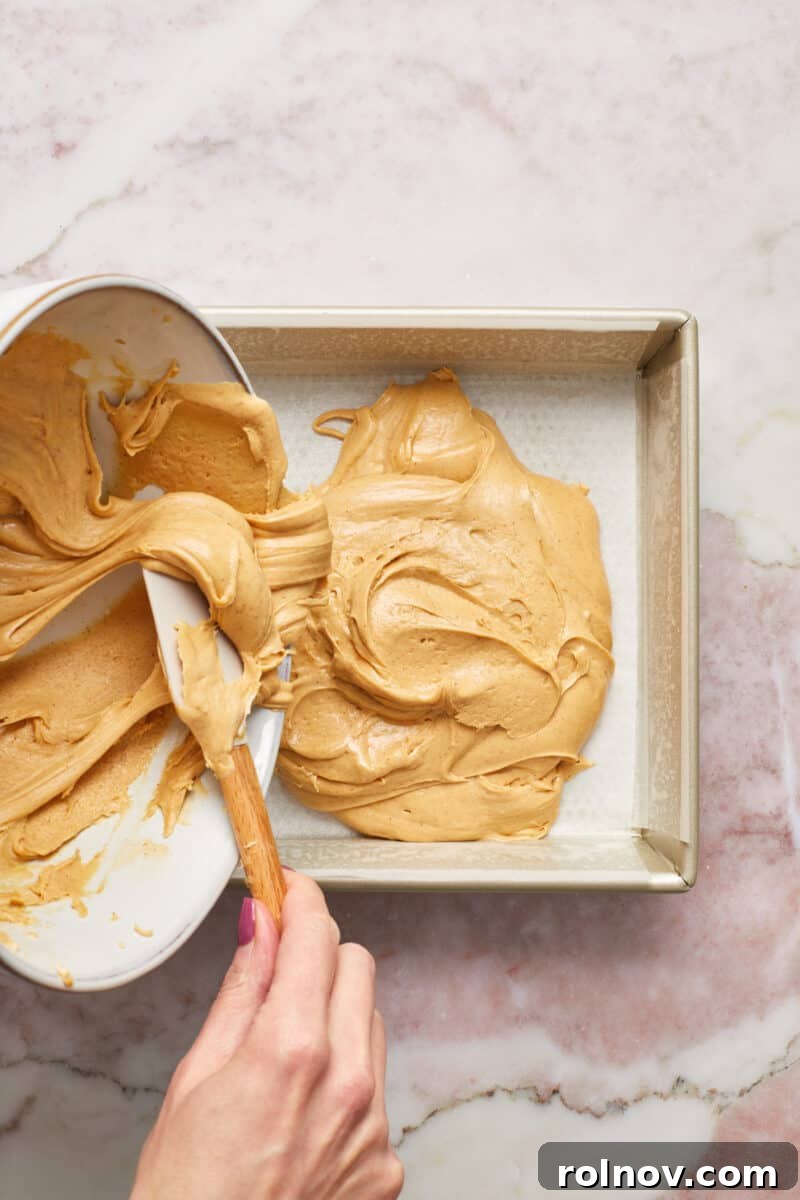 Effortless Peanut Butter Fudge 7 Peanut butter fudge mixture poured into parchment paper lined baking dish.
