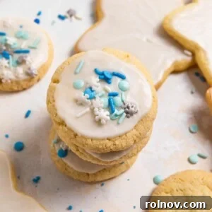 Stack of egg free sugar cookies with white icing and blue and white sprinkles.