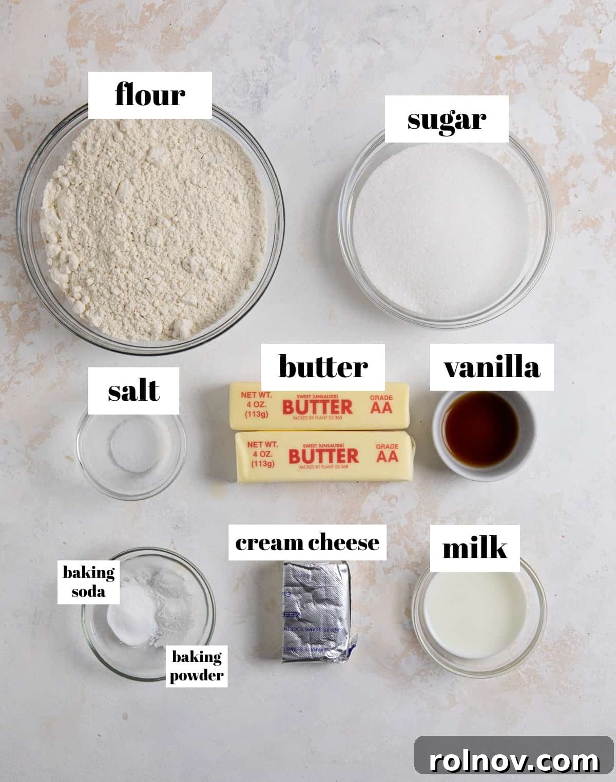An overhead shot displays the essential ingredients laid out for making eggless sugar cookies, including flour, milk, cream cheese, baking soda, and other fresh components.