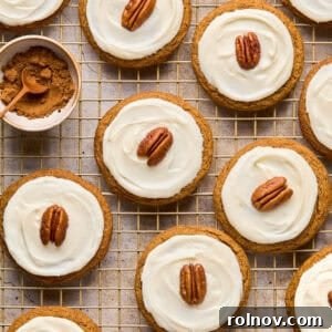 Iced molasses cookies with pecan half on top arranged on cooling rack.