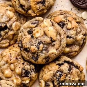 Oreo chocolate chip cookies arranged on surface with white chocolate chips and crumbs around them.