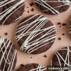 Chocolate cake mix cookies with white chocolate drizzle surrounded by cookie crumbs.