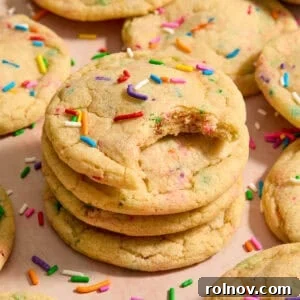Stack of funfetti rainbow sprinkle filled cookies with bite taken from the cookie on top of stack.